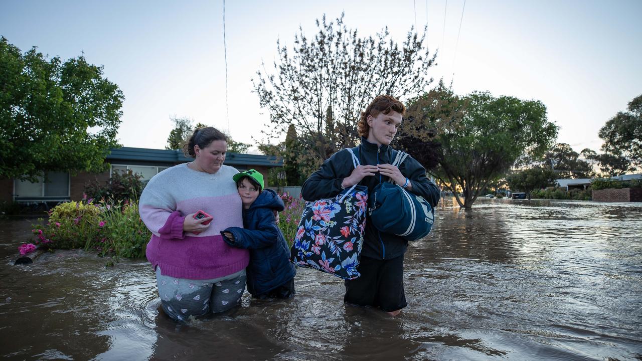 A family leaves their flooded home. Picture: Jason Edwards