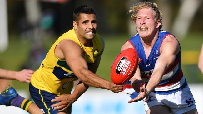 Travis Schiller of the Dogs handballs against the Eagles.