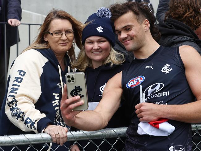 Tasmanian draftee Lachie Cowan, who will make his AFL debut on Thursday, poses with Carlton fans at training. Picture by Michael Klein