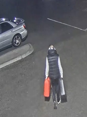 One of the suspects carrying cans of petrol to be used to destroy their getaway car. Picture: VicPol