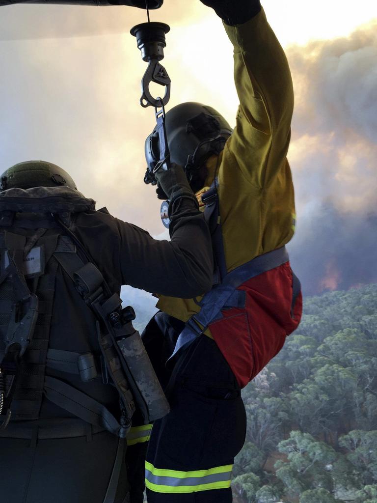 Rural Fire Service employee, Mr Allen Madden prepares to be winched down in the Lithgow area by Petty Officer Aircrewman Jason Wickman from an 808 Squadron MRH90 Taipan Military Support Helicopter over the Grose Valley bushfire in the Blue Mountains National Park. Picture: ADF