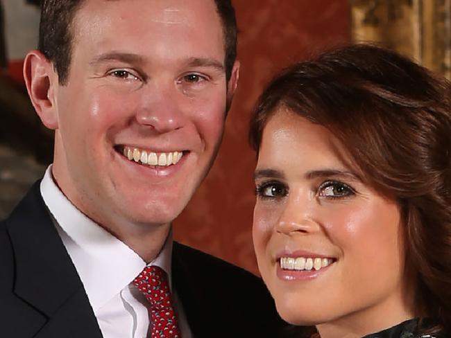 Britain's Princess Eugenie of York (R) poses with her fiance Jack Brooksbank in the Picture Gallery at Buckingham Palace in London on January 22, 2018, after the announcement of their engagement.  Britain's Princess Eugenie of York wears a dress by Erdem, shoes by Jimmy Choo and a ring containing a padparadscha sapphire surrounded by diamonds. Britain's Princess Eugenie of York has got engaged, Buckingham Palace announced January 22, 2018, lining up a second royal wedding this year at the church where Prince Harry will tie the knot.  / AFP PHOTO / POOL / Jonathan Brady