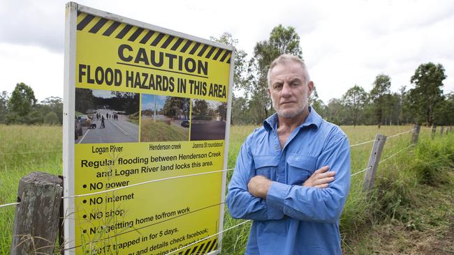 Jimboomba grazier Scott Nicholls with his sign warning of flooding on his property in Jimboomba. PHOTO: AAP/Sarah Marshall