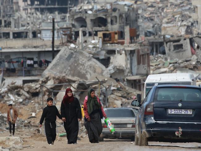 TOPSHOT - Displaced Palestinians walk through a muddy road amid the destruction in Jabalia in the northern Gaza Strip on February 6, 2025, during a truce in the war between Israel and Hamas. In hunger-stricken makeshift shelters set up in former schools, bombed-out houses and cemeteries across the Gaza Strip, devastated by 15 months of war between Hamas and Israel, hundreds of thousands lack even plastic sheeting to protect from winter rains and biting winds, aid workers say. (Photo by Bashar TALEB / AFP)