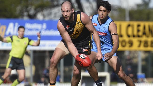 Glenelg’s Aaron Joseph gets a handball away in front of Sturt’s Shane McAdam at the Bay. Picture: Naomi Jellicoe.