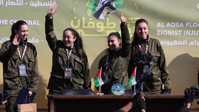 Israeli hostages, left to right, Naama Levy, Liri Albag, Daniella Gilboa and Karina Ariev, wave from a stage before Hamas fighters hand them over to a team from the Red Cross in Gaza City on Saturday. Picture: Omar Al-Aattaa / AFP