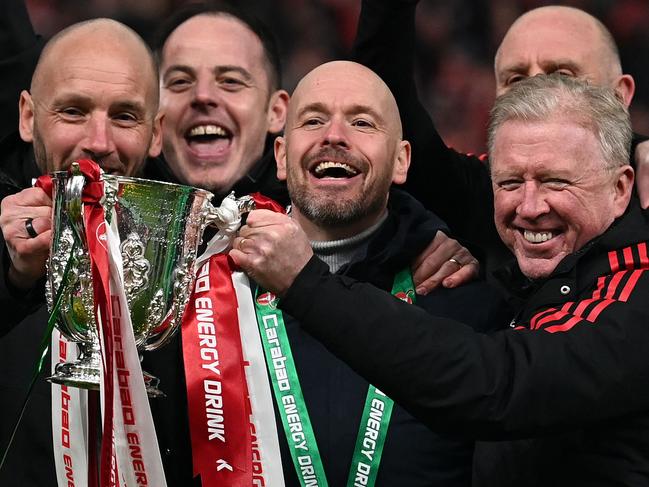 Manchester United manager Erik ten Hag (C) and his assistants celebrate with the trophy. Picture: Glyn Kirk/AFP