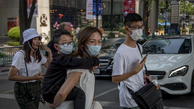 Chinese family wearing face masks walk in a pedestrian crossing in Bangkok, Thailand Picture AP Photo/Gemunu Amarasinghe