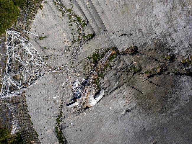 This aerial view shows the damage at the Arecibo Observatory after one of the main cables holding the reciever broke in Arecibo, Puerto Rico, on December 1, 2020. - The radio telescope in Puerto Rico, which once starred in a James Bond film, collapsed Tuesday when its 900-ton receiver platform fell 450 feet (140 meters) and smashed onto the radio dish below. (Photo by Ricardo ARDUENGO / AFP)