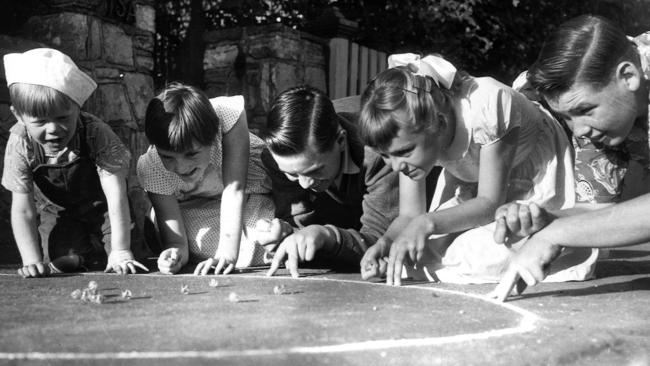 Children crowd around a chalk circle to knock out their mates’ marbles, 1958.