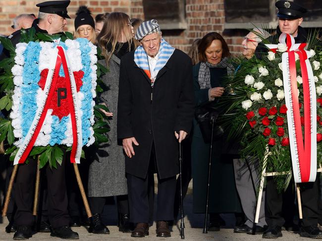 Holocaust survivor Stanislaw Zalewski (C) attends a ceremony as survivors, relatives and representatives of the Memorial and Museum Auschwitz-Birkenau lay wreaths and light candles at the so-called Death Wall next to the former Block 11 of the former Auschwitz I main camp in Oswiecim, Poland on January 27, 2025, during commemorations on the 80th anniversary of the liberation of the German Nazi concentration and extermination camp Auschwitz-Birkenau by the Red Army. (Photo by Wojtek RADWANSKI / AFP)