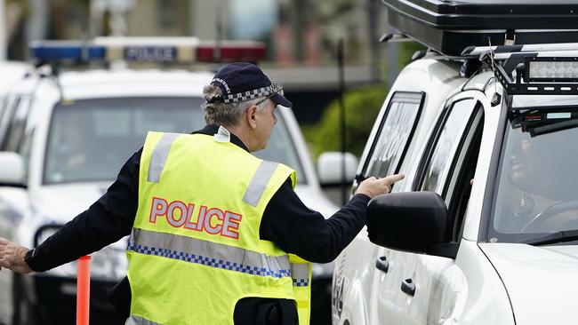 A Queensland police officer speaks with a motorist at a checkpoint at Coolangatta on the Queensland-New South Wales border. Picture: AAP Image/Dave Hunt