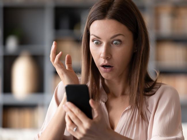 Head shot close up young shocked woman looking at mobile phone screen, received bank debt notification. Stunned frustrated lady reading sms with unbelievable news on smartphone, making big eyes. scam generic