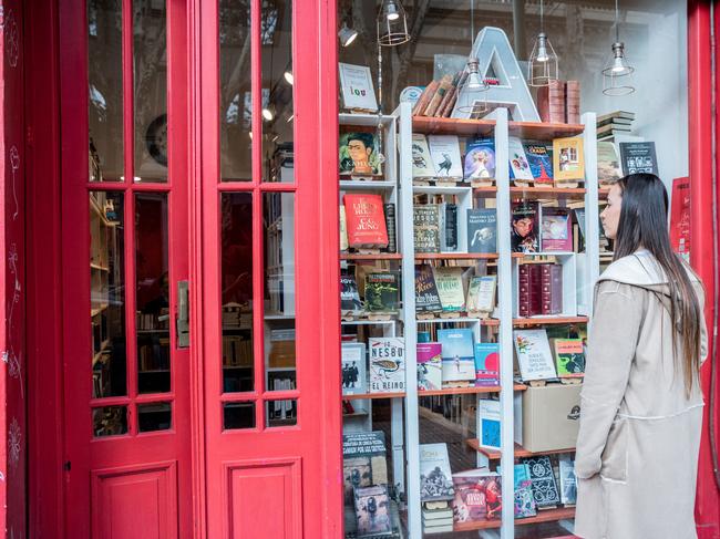 Young woman looking books on library showcase