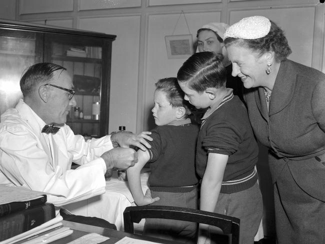 News. 18/6/1956 First shots of Salk anti-polio vaccine being given by Health and Medical Services deputy director Dr DW Johnson in Brisbane. On the receiving end are Clem, 7, left, and Paul, 9, sons of the Premier Vince Gair, pictured with their mother. Picture by Bob Millar jnr K8596 pub 19/6/56 The Courier-Mail Photo Archive.