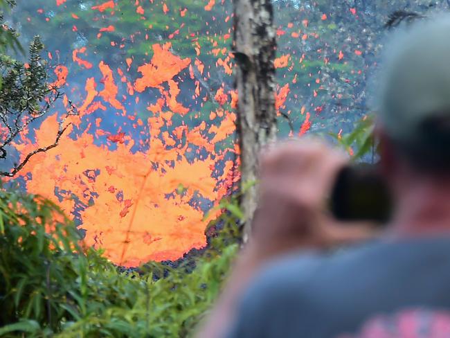 TOPSHOT - A man watches as lava is seen sewing from a fissure in the Leilani Estates subdivision near the town of Pahoa on Hawaii's Big Island on May 4, 2018 as up to 10,000 people were asked to leave their homes following the eruption of the Kilauea volcano that came after a series of recent earthquakes. / AFP PHOTO / Frederic J. BROWN