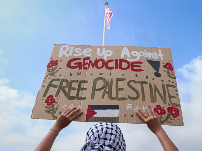 KUALA LUMPUR - OCTOBER 22: A demonstrator holds a placard reading "Rise up against genocide! Free Palestine" during a Freedom for Palestine rally at Merdeka Square on October 22, 2023, in Kuala Lumpur, Malaysia. On October 7, the Palestinian militant group Hamas launched the largest surprise attack from Gaza in a generation, sending thousands of missiles and an unknown number of fighters by land, who shot and kidnapped Israelis in communities near the Gaza border. The attack prompted retaliatory strikes on Gaza and a declaration of war by the Israeli prime minister. (Photo by Annice Lyn/Getty Images)