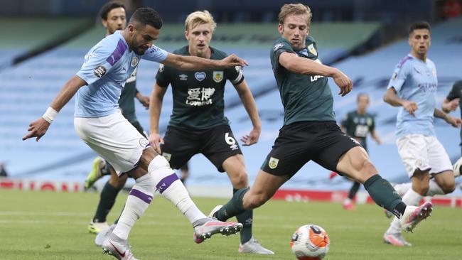 Manchester City’s Riyad Mahrez, left, kicks the ball past Burnley’s Charlie Taylor to score