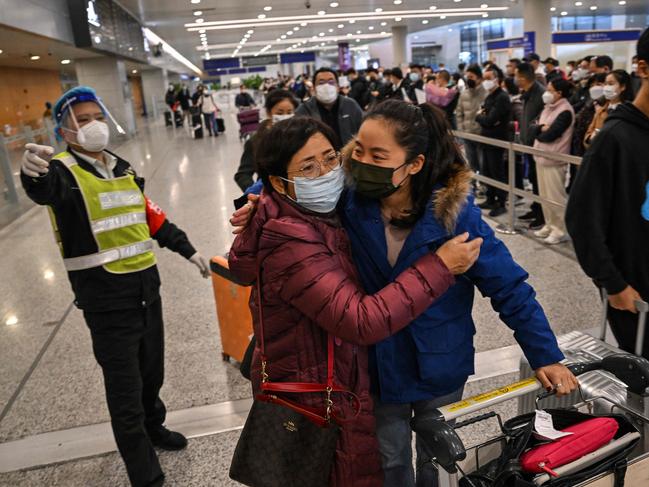 A passenger (R) receives a hug while leaving the arrival area of international flights at the Shanghai Pudong International Airport, in Shanghai on January 8, 2023. - China lifted quarantine requirements for inbound travellers on January 8, ending almost three years of self-imposed isolation even as the country battles a surge in Covid cases. (Photo by Hector RETAMAL / AFP)