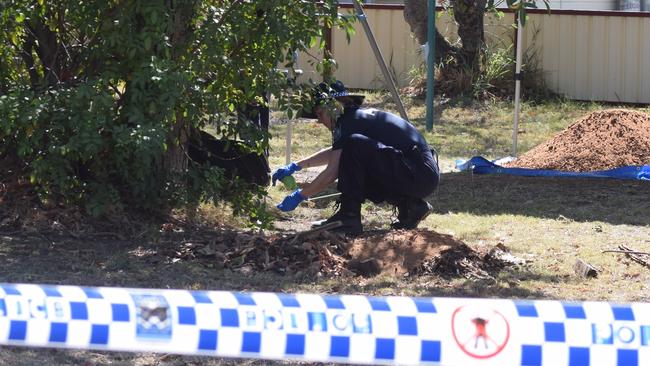 A police officer sifts soil from the backyard of a Chinchilla home where a crime scene has been established for the past two days.