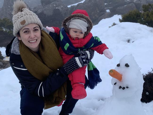 Kym Nissen and Evie Izatt with a snow man.After the road to the top of Mt Wellington was cleared hundreds of locals hit the snow.