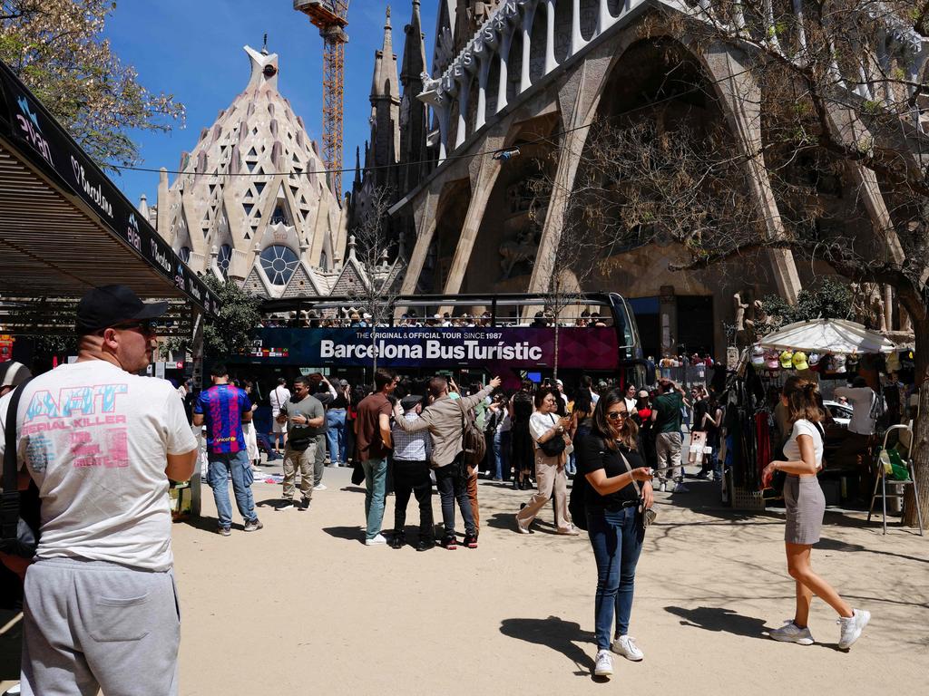 Tourists walk past the Sagrada Familia basilica in Barcelona.