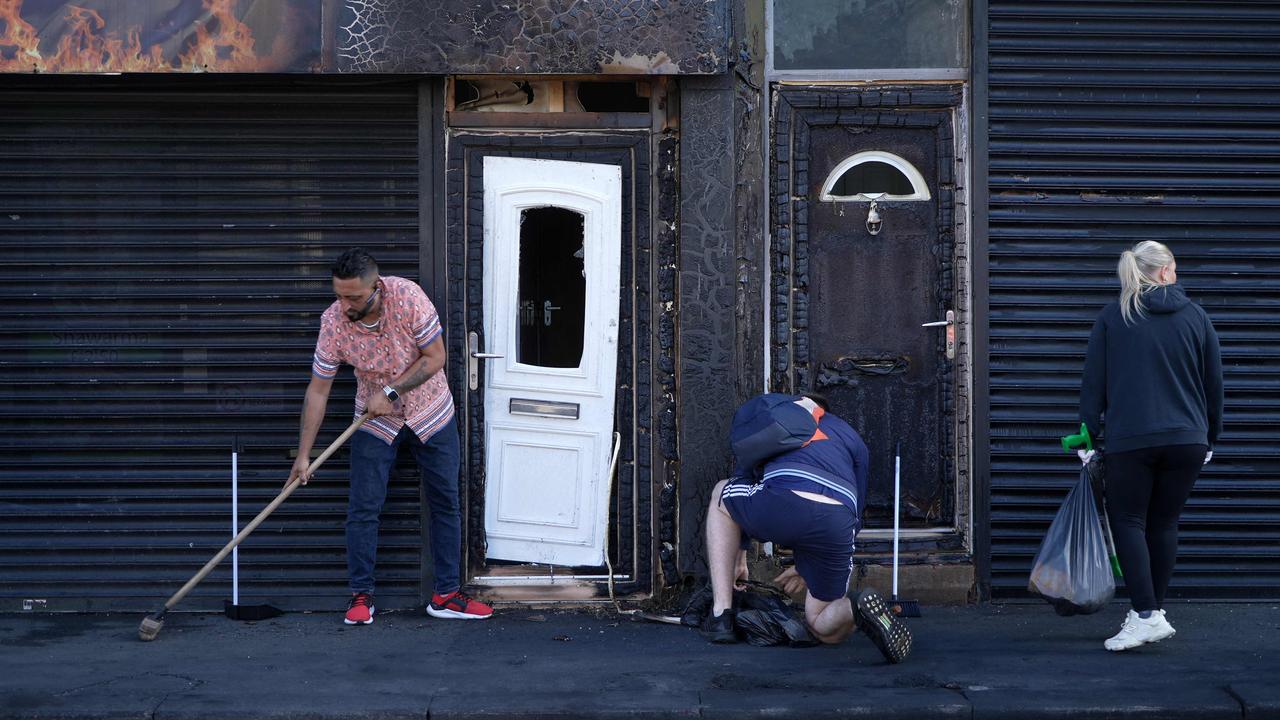 Restaurant owner Luqman Khan clears debris from the street in front of his restaurant after the riots. Picture: Yelim Lee/AFP