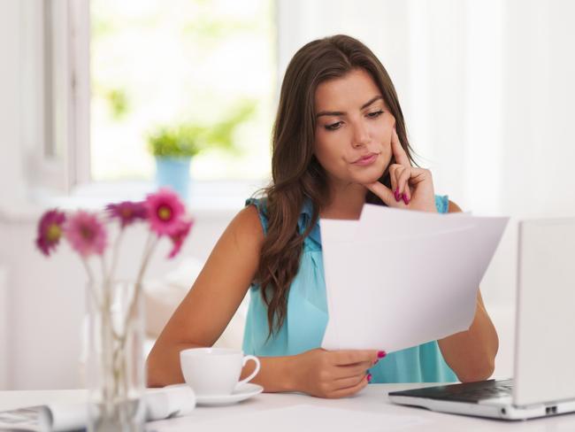 A woman with her computer and bank statements sitting at a desk. She is also analysing her superannuation statement. Picture: iStock.