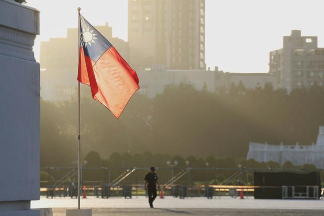 A man walks past a hoisted Taiwanese flag at the Chiang Kai-shek Memorial Hall in Taipei on Tuesday