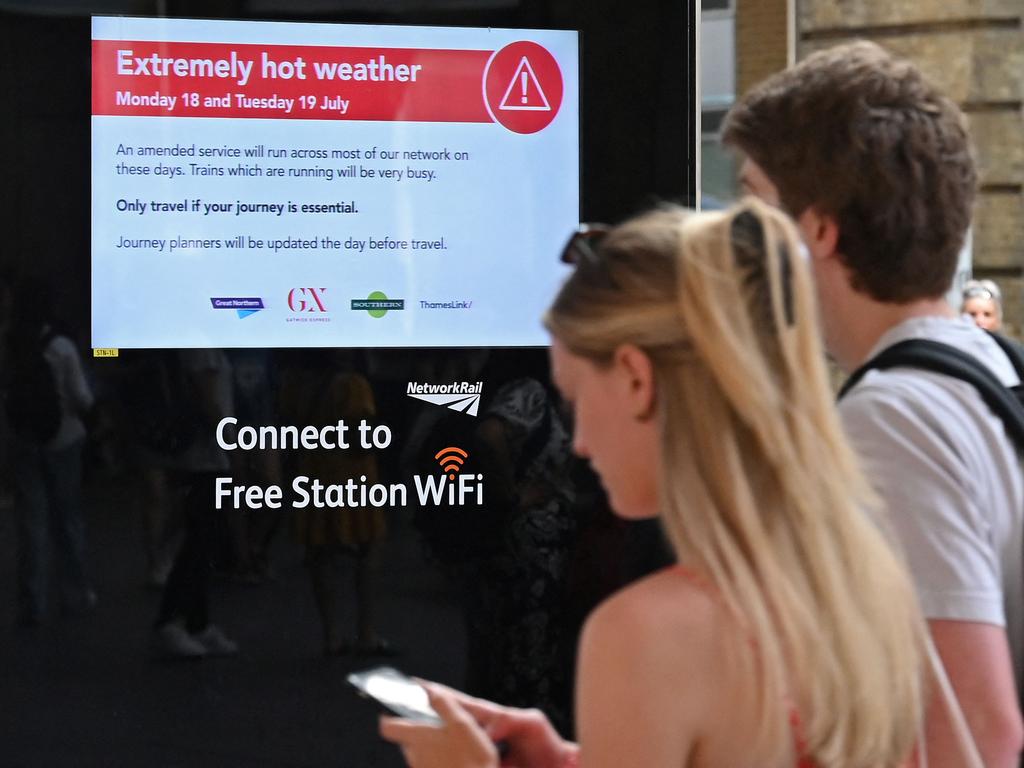 Rail passengers pass an electronic sign warning of 'Extremely hot weather' at Kings Cross station in London. Picture: AFP