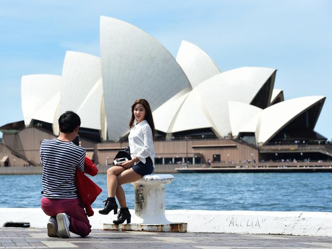 A man takes a photograph of a woman front of the Sydney Opera House in Sydney, Thursday, Oct. 6, 2016. NSW's net debt will be wiped out following a bumper budget surplus of $4.7 billion for the last financial year, Treasurer Gladys Berejiklian. (AAP Image/Mick Tsikas) NO ARCHIVING