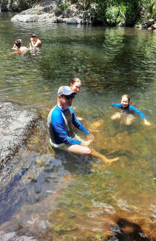 Katrina Williams snapped this photo of her husband and their two daughters at Crystal Cascades near Cairns. The overseas tourists are captured in the background and soon after this photo was taken, they were drowning.