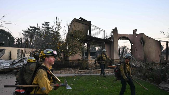 Firefighters walk around a neighbourhood turning off gas valves at homes as the Eaton Fire continues to burn in Altadena, California. Picture: AFP