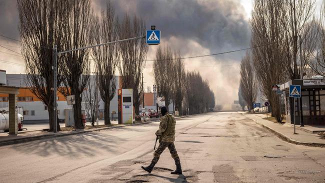 A Ukrainian serviceman stands guard near a burning warehouse hit by a Russian shell in the suburbs of Kyiv. Picture: AFP