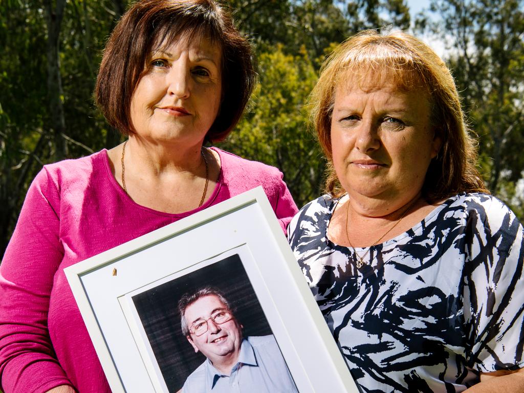 Carmel Schwartz and Sharon Howard standing together with a framed photo of Peter Howard. Peter took his own life after years of workplace bullying. The family spoke with the review Picture: Morgan Sette.