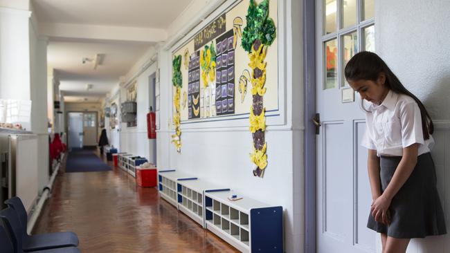 Naughty school girl stands in the corridor after being sent out of class.