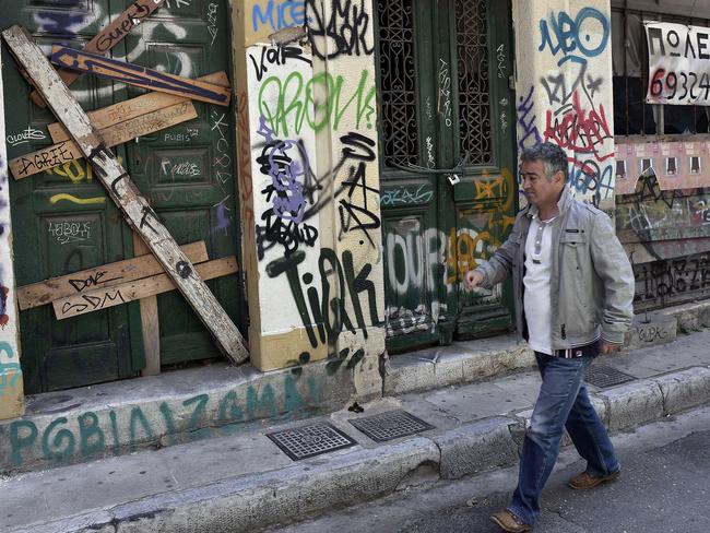 A man walks past abandoned buildings with ‘for sale’ signs in central Athens ... Greece is a potent warning for Australia’s possible future. Picture: AFP Photo / Louisa Gouliamaki
