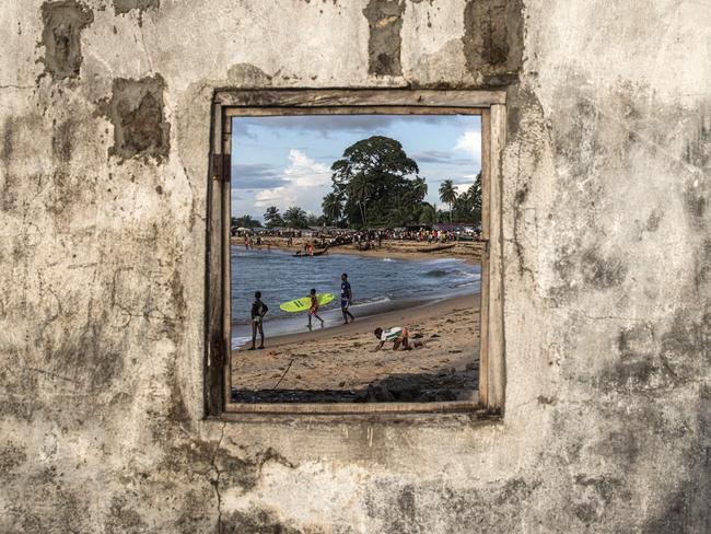 A young surfer carries a surfboard in Robertsport, Liberia. The Robertsport Surf Club - together with the aid of NGO, Provide The Slide, have managed to provide surfboards and help send the children to school. Picture: John Wessels/AFP