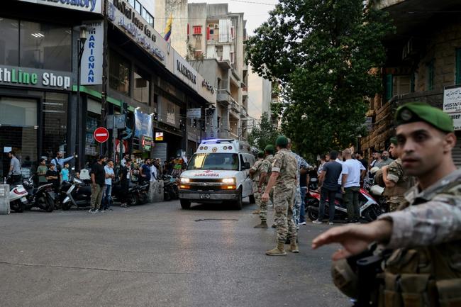 Lebanese soldiers stand guard as an ambulance rushes wounded people to hospital in Beirut