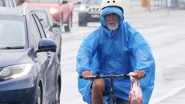 A man rides his bike alongside the traffic on Mulgrave Road in the wet weather. Picture: Brendan Radke