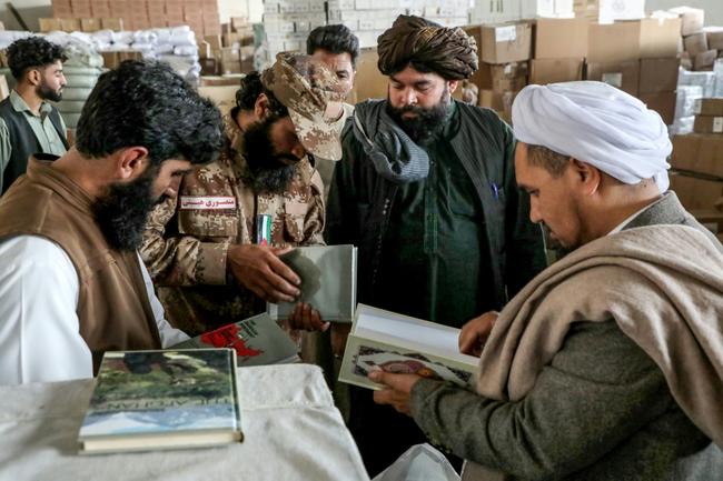 Taliban government personnel evaluate books imported from Iran to Afghanistan at a customs warehouse in Herat