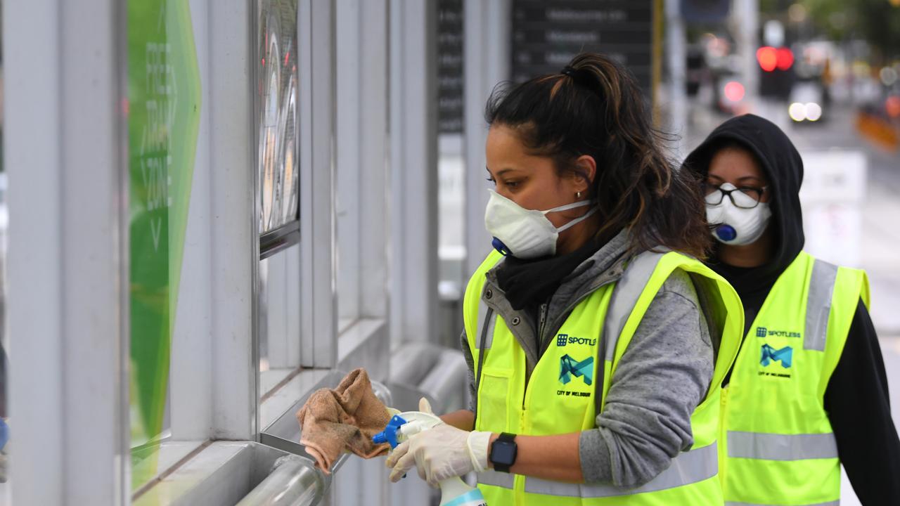 A member of a cleaning team is seen working at tram shelter in Melbourne. Picture: AAP Image/James Ross.