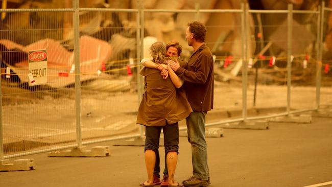 Shocked residents console each other amid razed buildings in the main street of Cobargo on Wednesday. Picture: Stuart McEvoy