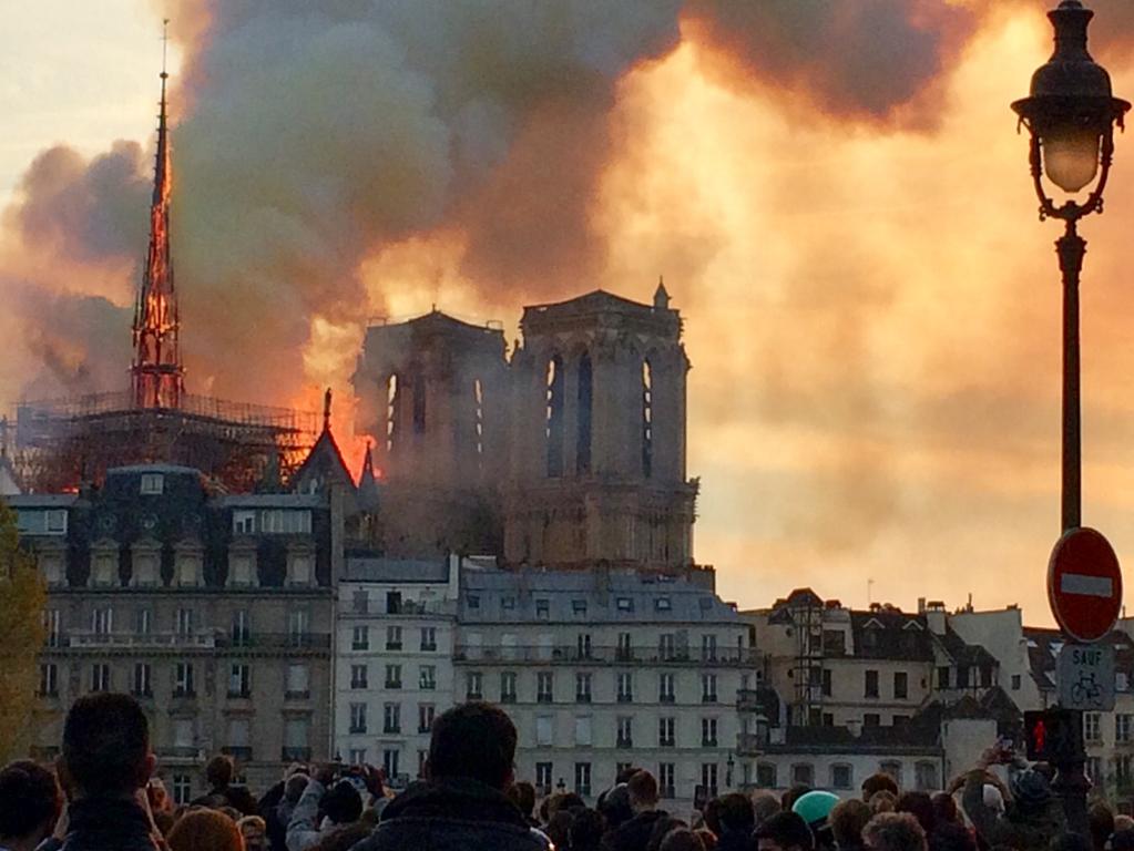 People looking at smoke and flames rising during a fire at the landmark Notre-Dame Cathedral in central Paris. Picture: AFP