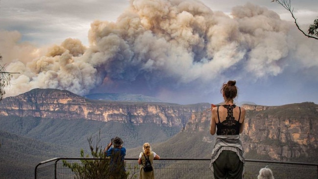 People watch as smoke billows from a fire in the Blue Mountains National Park at Evans lookout in Blackheath on Monday. Picture: Nina Lipscombe Art