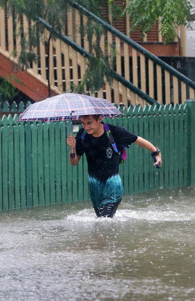 Rigby Wilshire wades through flood waters to get to his home in East Brisbane. Picture: Darren England.