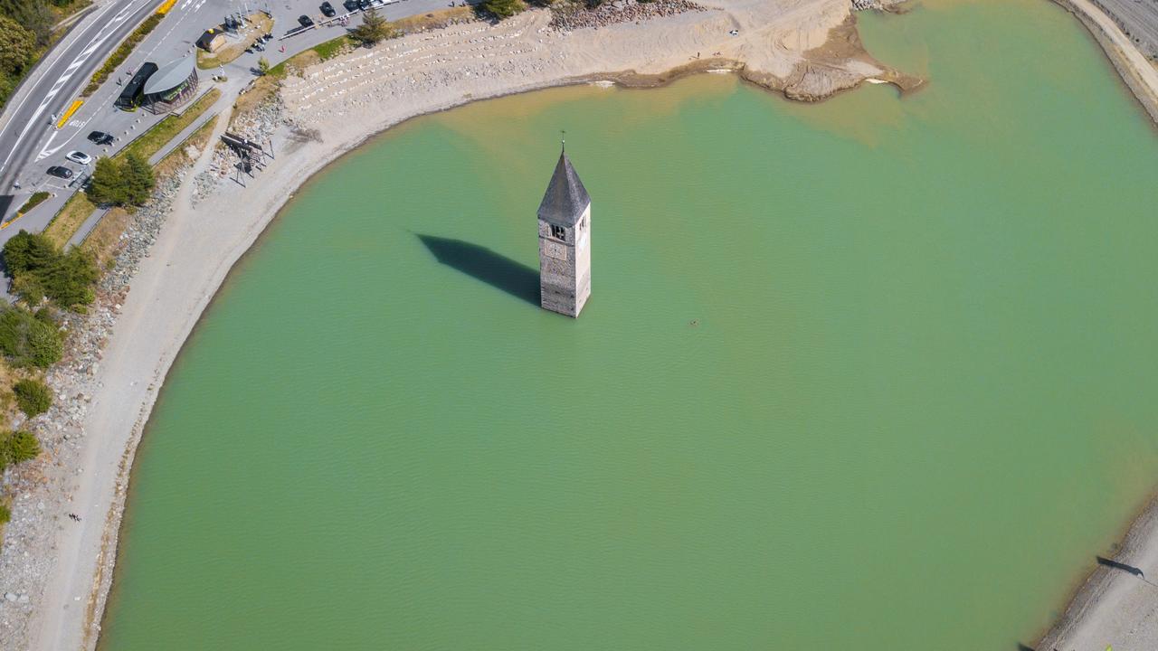 Drone aerial view of the old bell tower of the village rising out of Lake Resia in Curon, Italy.