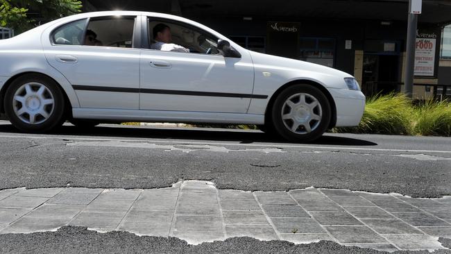 Bitumen on Hindley Street peeling away – after it was applied to fix the slippery pavers, visible underneath.