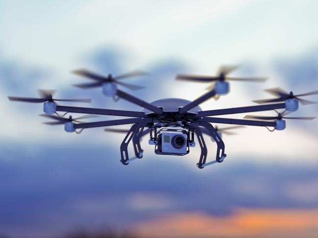 a drone flying in a cloudy sky where the sun goes down