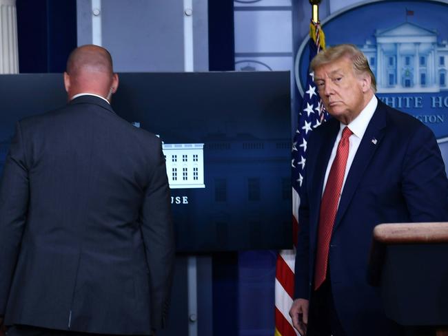 US President Donald Trump is being removed by a member of the secret service from the Brady Briefing Room of the White House in Washington, DC, on August 10, 2020. (Photo by Brendan Smialowski / AFP)